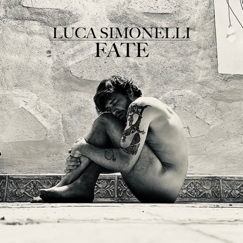 Fate cover art: Luca Simonelli sitting curled against a bare wall, in black and white